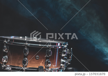 Close-up of a snare drum on a dark background with smoke, copy space. Close-up of a snare drum on a dark background with smoke, copy space. 137031870
