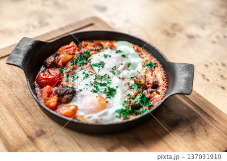 Close-up of traditional shakshuka in a frying pan on a wooden background. 137031910