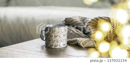 Cozy background with shiny gray cup, bokeh lights and knitted element. 137032154