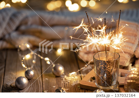 Cozy Christmas background with glowing sparklers and decor details. Cozy Christmas background with glowing sparklers and decor details. 137032164