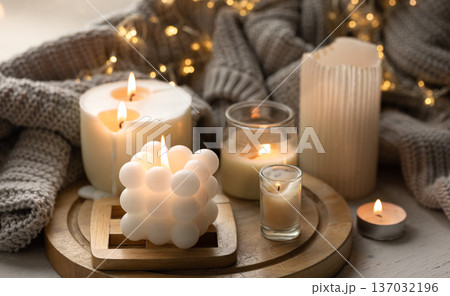 A cozy composition with candles, a knitted element and a garland. 137032196