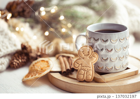 Beautiful cup with handmade gingerbread boy on a cozy blurred background with lights. Beautiful cup with handmade gingerbread boy on a cozy blurred background with lights. 137032197