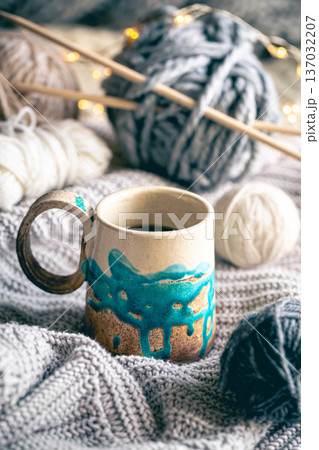 Cozy composition with a cup of coffee, threads and a knitted element. Cozy composition with a cup of coffee, threads and a knitted element. 137032207