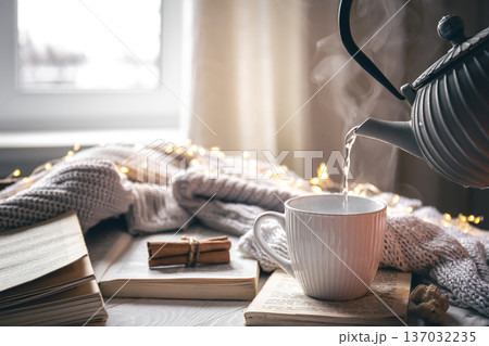 Cozy composition with a teapot, a cup and a book on a blurred background. Cozy composition with a teapot, a cup and a book on a blurred background. 137032235