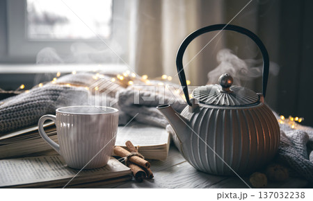Cozy composition with a teapot, a cup and a book on a blurred background. 137032238