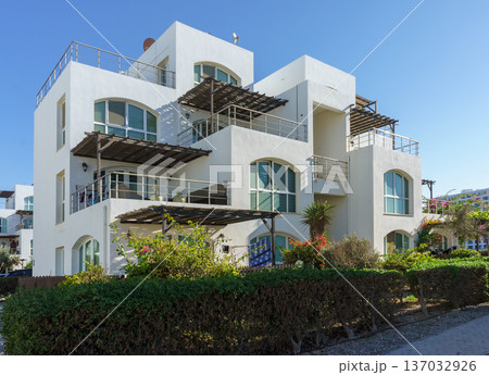 Charming coastal villa bathed in sunlight, surrounded by lush greenery 137032926