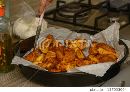 Uncooked Potato Wedges Arranged on Parchment-Lined Baking Tray Uncooked Potato Wedges Arranged on Parchment-Lined Baking Tray 137033064
