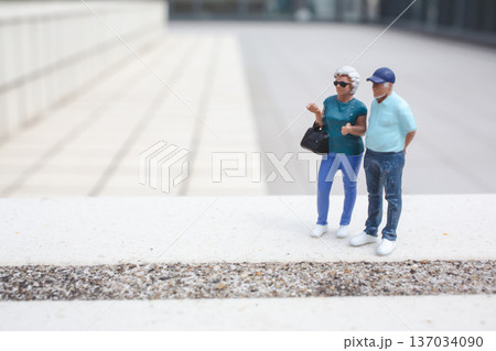 Miniature couple stands together on elevated outdoor platform 137034090