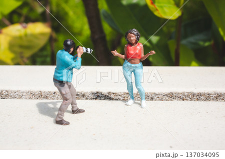 Miniature photographer captures model posing beside green foliage Miniature photographer captures model posing beside green foliage 137034095