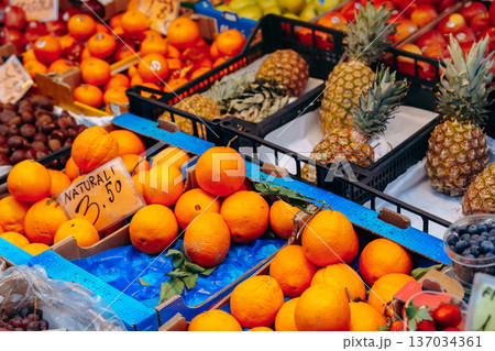 Fruit display at market with oranges and pineapples in clear view during daylight hours Fruit display at market with oranges and pineapples in clear view during daylight hours 137034361