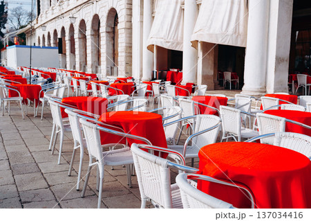 Outdoor dining area with red tables and white chairs in a historical location Outdoor dining area with red tables and white chairs in a historical location 137034416