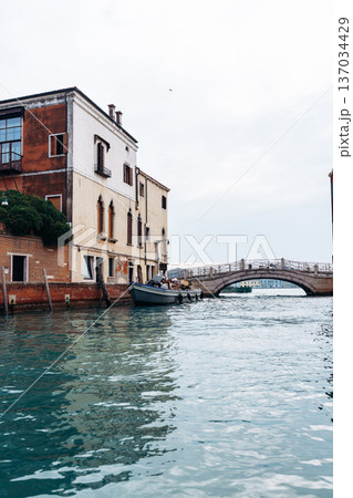 Quiet canal in Venice with a boat by the old buildings and a small bridge Quiet canal in Venice with a boat by the old buildings and a small bridge 137034429