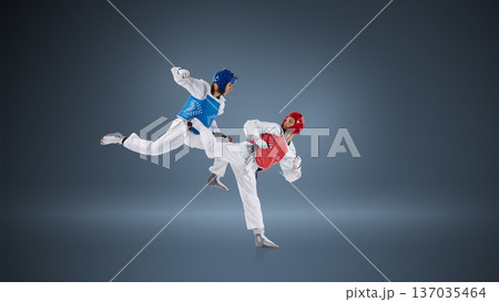 Professional taekwondo fighters in dynamic kick exchange on blue background wearing protective helmets and chest guards. Professional taekwondo fighters in dynamic kick exchange on blue background wearing protective helmets and chest guards. 137035464