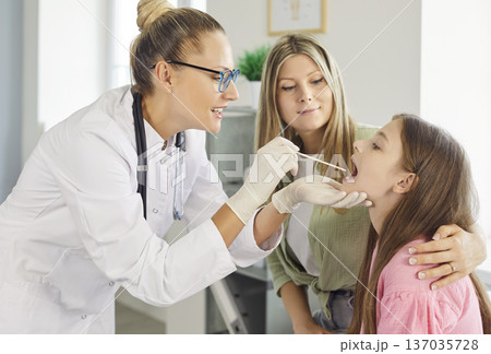 Pediatrician taking throat swab from child patient as mother supports in clinic 137035728
