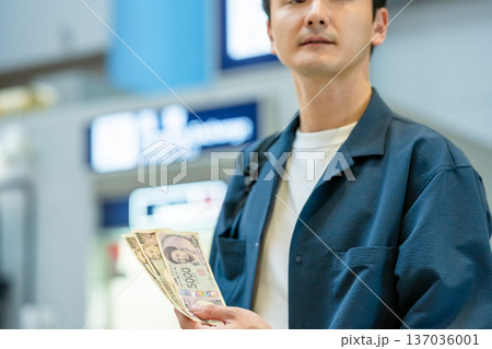 駅で日本円を持つ男性 ■撮影協力：関西国際空港（KIX） 137036001