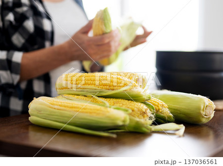 Woman Cooking Fresh Raw Corn In Kitchen 137036561