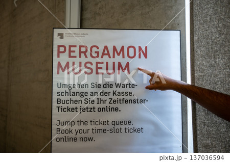 Berlin, germany, august 16, 2023. A hand pointing at a sign indicating the pergamon museum, offering information about booking time-slot tickets online in berlin 137036594