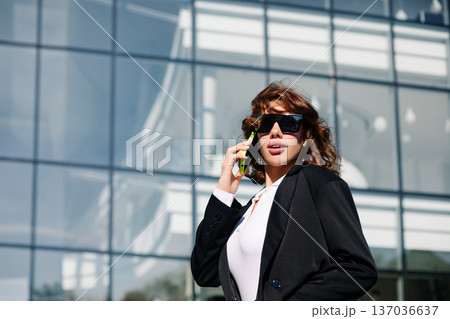 Modern businesswoman talking on phone near office building exterior Modern businesswoman talking on phone near office building exterior 137036637