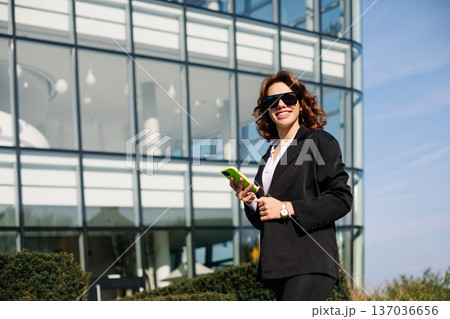 Happy Businesswoman Talking On Phone And Smiling In Sunlight Outdoors 137036656
