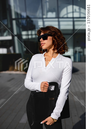 Professional businesswoman holding leather briefcase walking in city 137036681