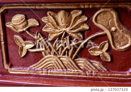 Gold floral relief carving on red lacquered wood Gold floral relief carving on red lacquered wood 137037329
