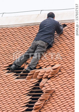 Roofer repairing terracotta tile roof on residential house Roofer repairing terracotta tile roof on residential house 137037337