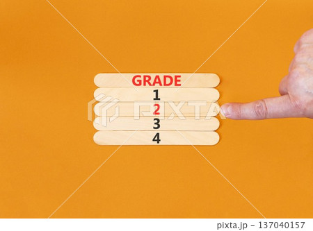 Time to grade 2 symbol. Concept word Grade 1 2 3 4 on beautiful wooden sticks. Businessman's hand. Beautiful orange background. Business planning and time to grade 2 concept. Copy space. Time to grade 2 symbol. Concept word Grade 1 2 3 4 on beautiful wooden sticks. Businessman's hand. Beautiful orange background. Business planning and time to grade 2 concept. Copy space. 137040157