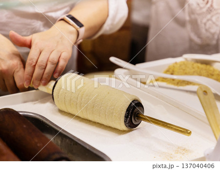 Hands preparing traditional pastry on rolling pin with ingredients nearby Hands preparing traditional pastry on rolling pin with ingredients nearby 137040406