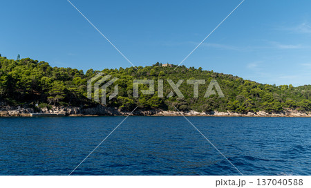 Beautiful clear waters and lush greenery surround the rocky coastline of Lokrum Island. Beautiful clear waters and lush greenery surround the rocky coastline of Lokrum Island. 137040588
