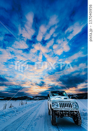 広がる冬の空と雪道を進むオフロード車 北海道の夕景 広がる冬の空と雪道を進むオフロード車 北海道の夕景 137040956