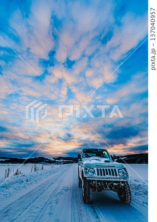 冬の北海道の雪道と四輪駆動車、ドラマチックな雲と夕焼け空 冬の北海道の雪道と四輪駆動車、ドラマチックな雲と夕焼け空 137040957