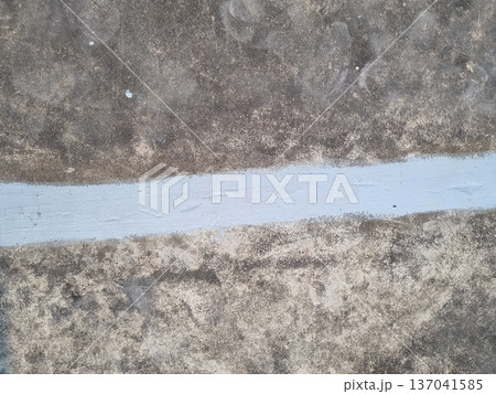 Professional waterproofing application on concrete surface with a horizontal light blue painted stripe. Grungy industrial texture showing stains and signs of wear. 137041585