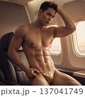 Handsome Male Model in Vibrant Fashion Swimwear Relaxing in Luxury Airline First Class Suite 137041749