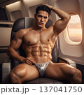 Handsome Male Model in Vibrant Fashion Swimwear Relaxing in Luxury Airline First Class Suite 137041750