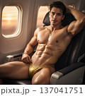 Handsome Male Model in Vibrant Fashion Swimwear Relaxing in Luxury Airline First Class Suite 137041751