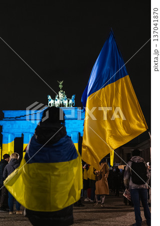 Protester Draped in Ukrainian Flag Faces Brandenburg Gate in Berlin 137041870
