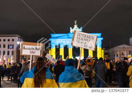 Protesters Hold Signs in Front of Brandenburg Gate Lit Blue and Yellow Protesters Hold Signs in Front of Brandenburg Gate Lit Blue and Yellow 137041877