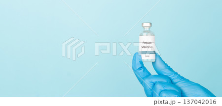 Doctor hand holding Rabies vaccine bottle on blue background. Vaccine used to prevent rabies virus infection. Doctor hand holding Rabies vaccine bottle on blue background. Vaccine used to prevent rabies virus infection. 137042016