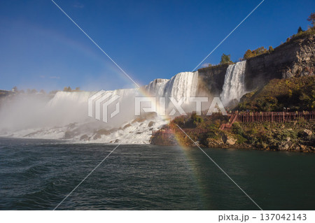 Niagara Falls waterfall with rainbow and observation walkway in misty landscape Niagara Falls waterfall with rainbow and observation walkway in misty landscape 137042143