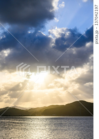 水面に差す光と山 137042197
