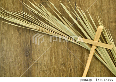 Palm sunday cross and palm branches on wood surface Palm sunday cross and palm branches on wood surface 137042355