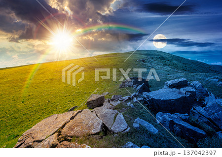 rocks and rolling hills in mountain landscape on summer solstice. day meet night. sun and moon over scenery with green grass on alpine meadow. astrology recreation tourism and wanderlust 137042397