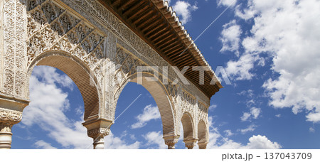 Arches in Islamic (Moorish) style (against the background of a beautiful sky with clouds) in Alhambra, Granada, Spain Arches in Islamic (Moorish) style (against the background of a beautiful sky with clouds) in Alhambra, Granada, Spain 137043709