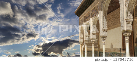 Arches in Islamic (Moorish) style (against the background of a beautiful sky with clouds) in Alhambra, Granada, Spain Arches in Islamic (Moorish) style (against the background of a beautiful sky with clouds) in Alhambra, Granada, Spain 137043716