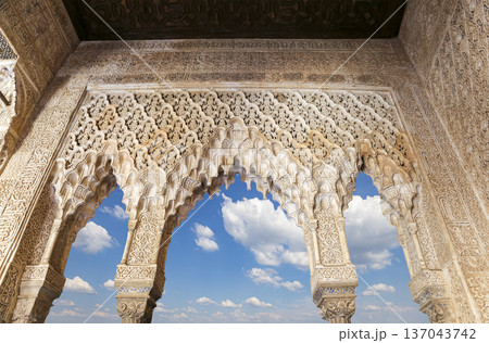 Arches in Islamic (Moorish) style (against the background of a beautiful sky with clouds) in Alhambra, Granada, Spain Arches in Islamic (Moorish) style (against the background of a beautiful sky with clouds) in Alhambra, Granada, Spain 137043742