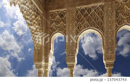 Arches in Islamic (Moorish) style (against the background of a beautiful sky with clouds) in Alhambra, Granada, Spain Arches in Islamic (Moorish) style (against the background of a beautiful sky with clouds) in Alhambra, Granada, Spain 137043743