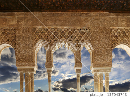 Arches in Islamic (Moorish) style (against the background of a beautiful sky with clouds) in Alhambra, Granada, Spain Arches in Islamic (Moorish) style (against the background of a beautiful sky with clouds) in Alhambra, Granada, Spain 137043748
