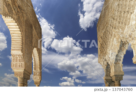 Arches in Islamic (Moorish) style (against the background of a beautiful sky with clouds) in Alhambra, Granada, Spain Arches in Islamic (Moorish) style (against the background of a beautiful sky with clouds) in Alhambra, Granada, Spain 137043760