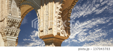 Arches in Islamic (Moorish) style (against the background of a beautiful sky with clouds) in Alhambra, Granada, Spain Arches in Islamic (Moorish) style (against the background of a beautiful sky with clouds) in Alhambra, Granada, Spain 137043783