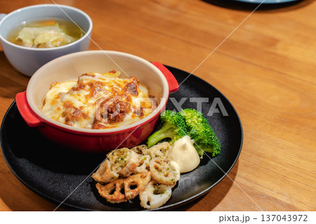 木のテーブルでグラタンを中心にした夕食ワンプレートと野菜スープ 木のテーブルでグラタンを中心にした夕食ワンプレートと野菜スープ 137043972